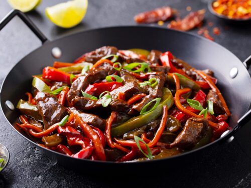 Beef and vegetables stir fry in a pan Dark background Close up