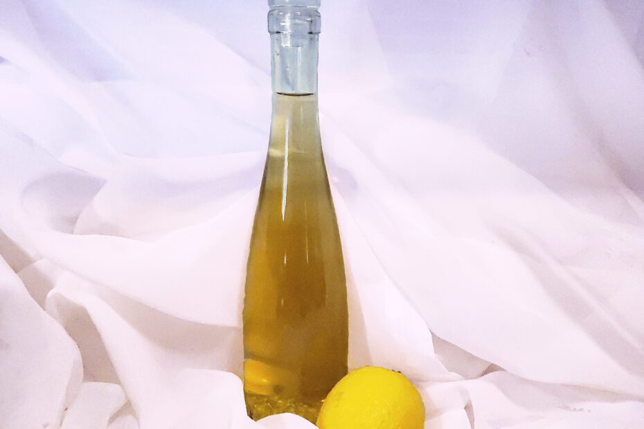 Bottle of limoncello with a lemon on a gauze background