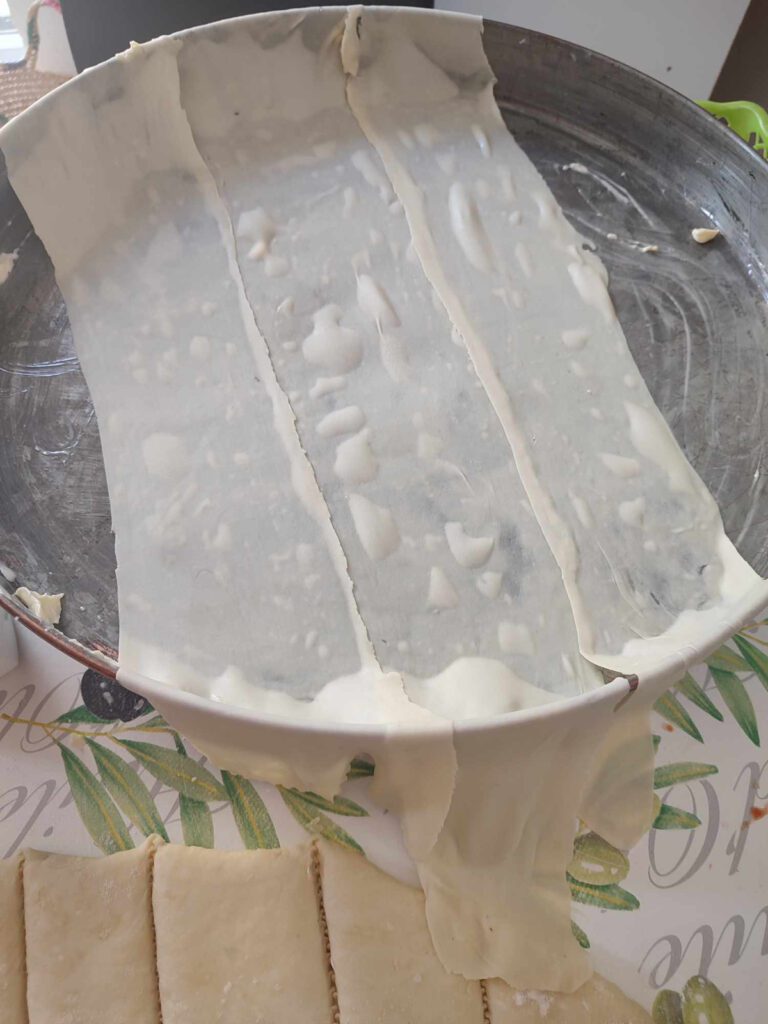 Homemade baklawa dough stretched across the pan